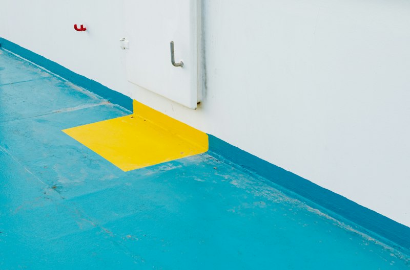 Blue and yellow coated floor beside a white wall