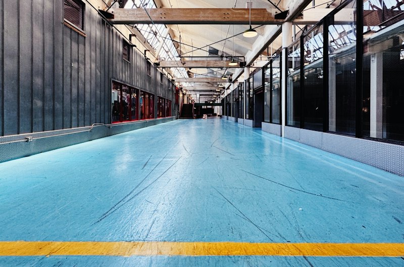 Large room with a blue coated floor and yellow safety line